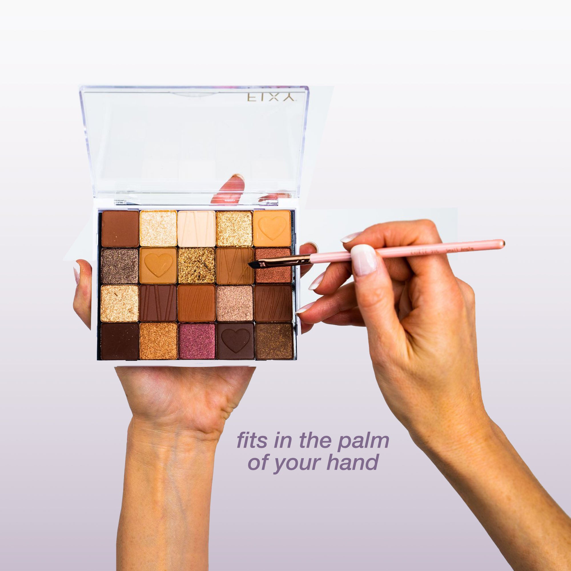 Hand holding a FIXY small clear makeup palette, filled with colorful eyeshadows and a brush applying makeup, demonstrating the palette&#39;s convenient size that fits in the palm of your hand for easy use and portability.